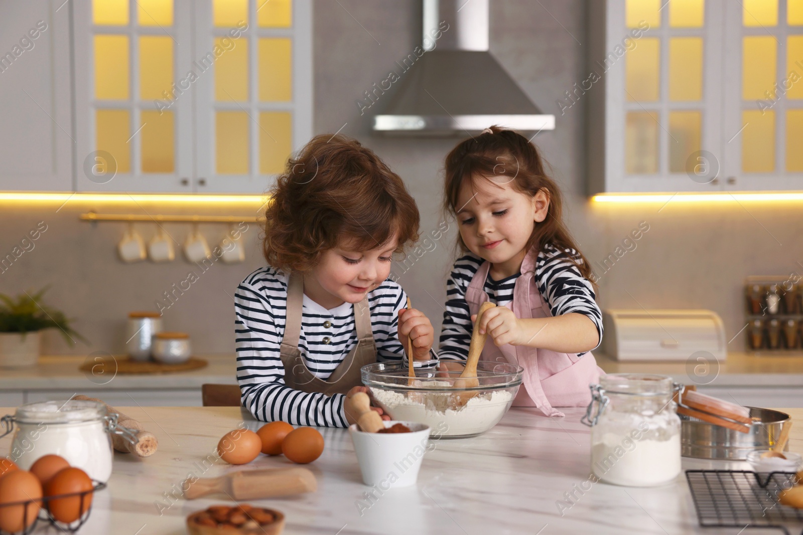 Cooking recipe. Cute children making dough for cookies at table in kitchen Photo of Cooking recipe. Cute children making dough for cookies at table in kitchen