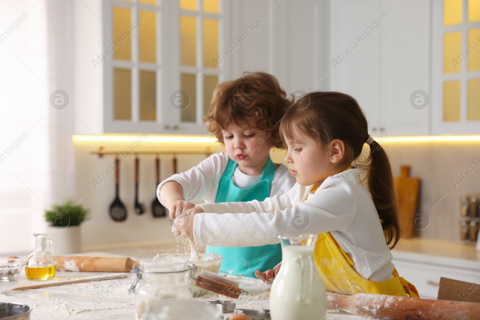 Cooking recipe. Cute children making dough for cookies at table in kitchen Photo of Cooking recipe. Cute children making dough for cookies at table in kitchen