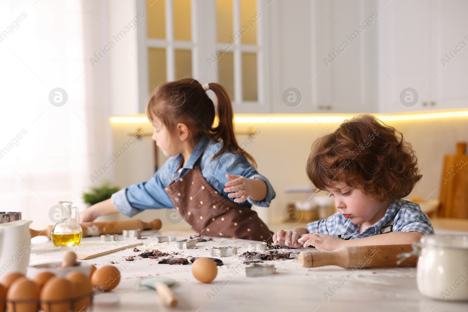 Cooking recipe. Little children cutting cookies with cutters at table in kitchen Photo of Cooking recipe. Little children cutting cookies with cutters at table in kitchen