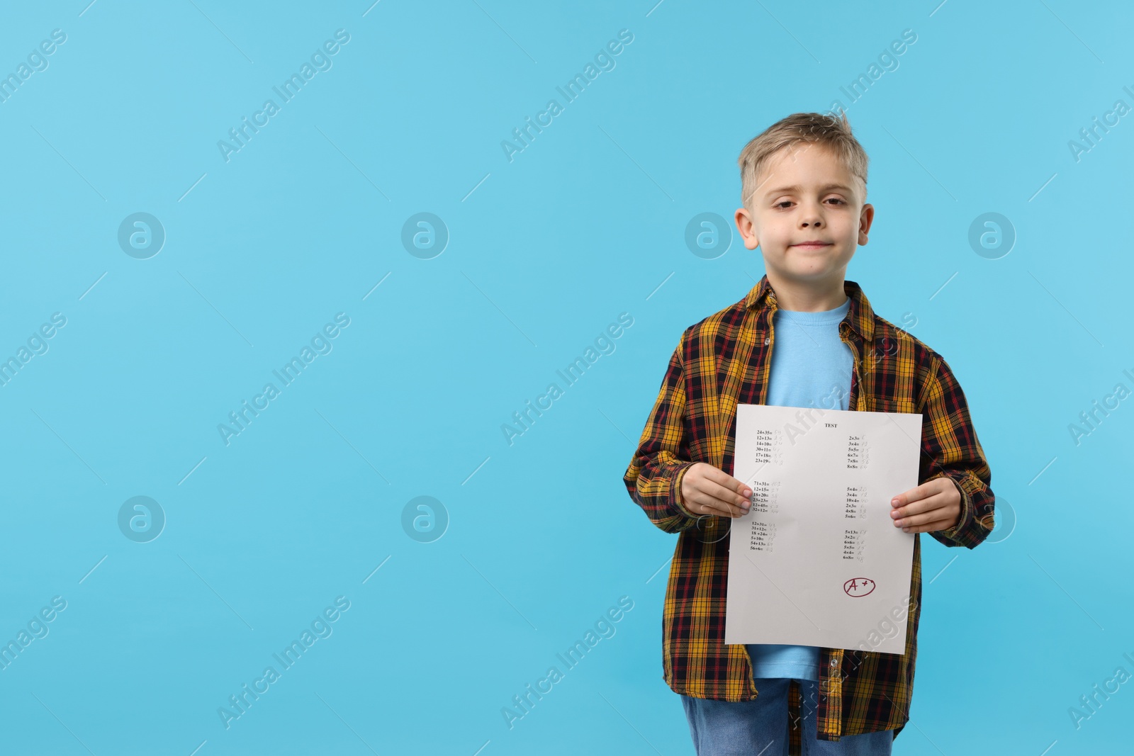 School grade. Little boy holding answer sheet with letter A and plus symbol on light blue background, space for text Photo of School grade. Little boy holding answer sheet with letter A and plus symbol on light blue background, space for text