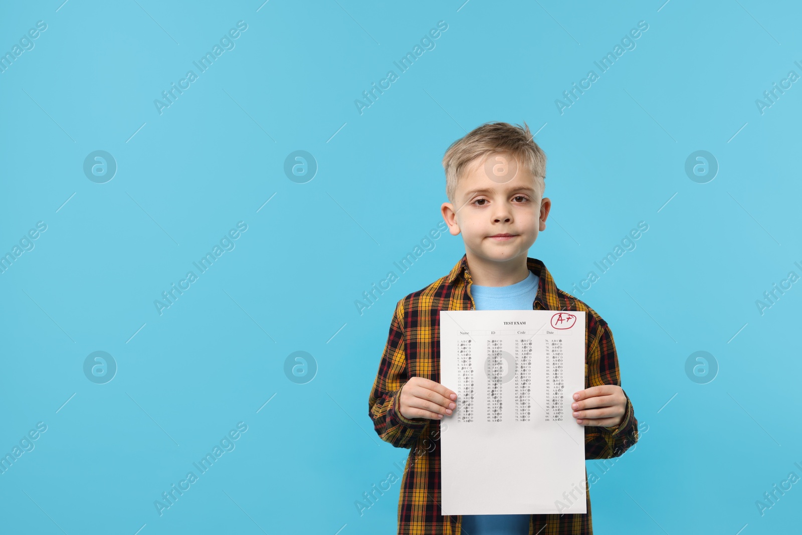 School grade. Little boy holding answer sheet with letter A and plus symbol on light blue background, space for text Photo of School grade. Little boy holding answer sheet with letter A and plus symbol on light blue background, space for text