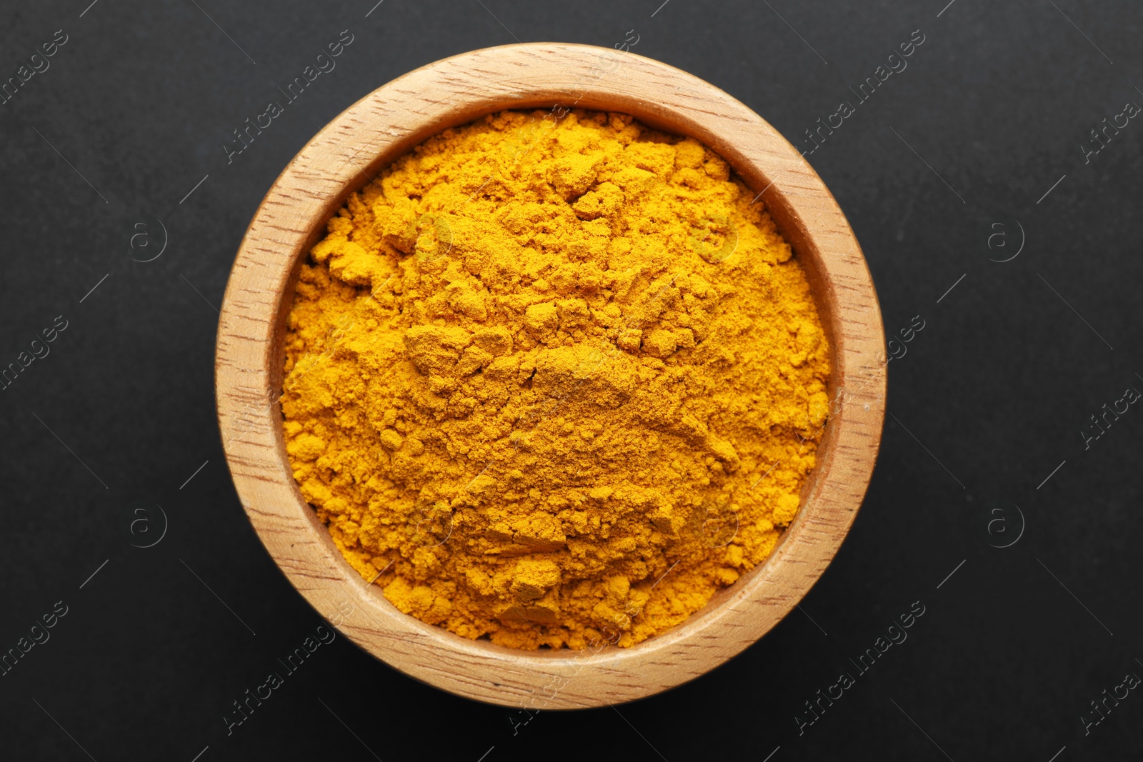 Turmeric powder in bowl on black background, top view. Aromatic spice Photo of Turmeric powder in bowl on black background, top view. Aromatic spice