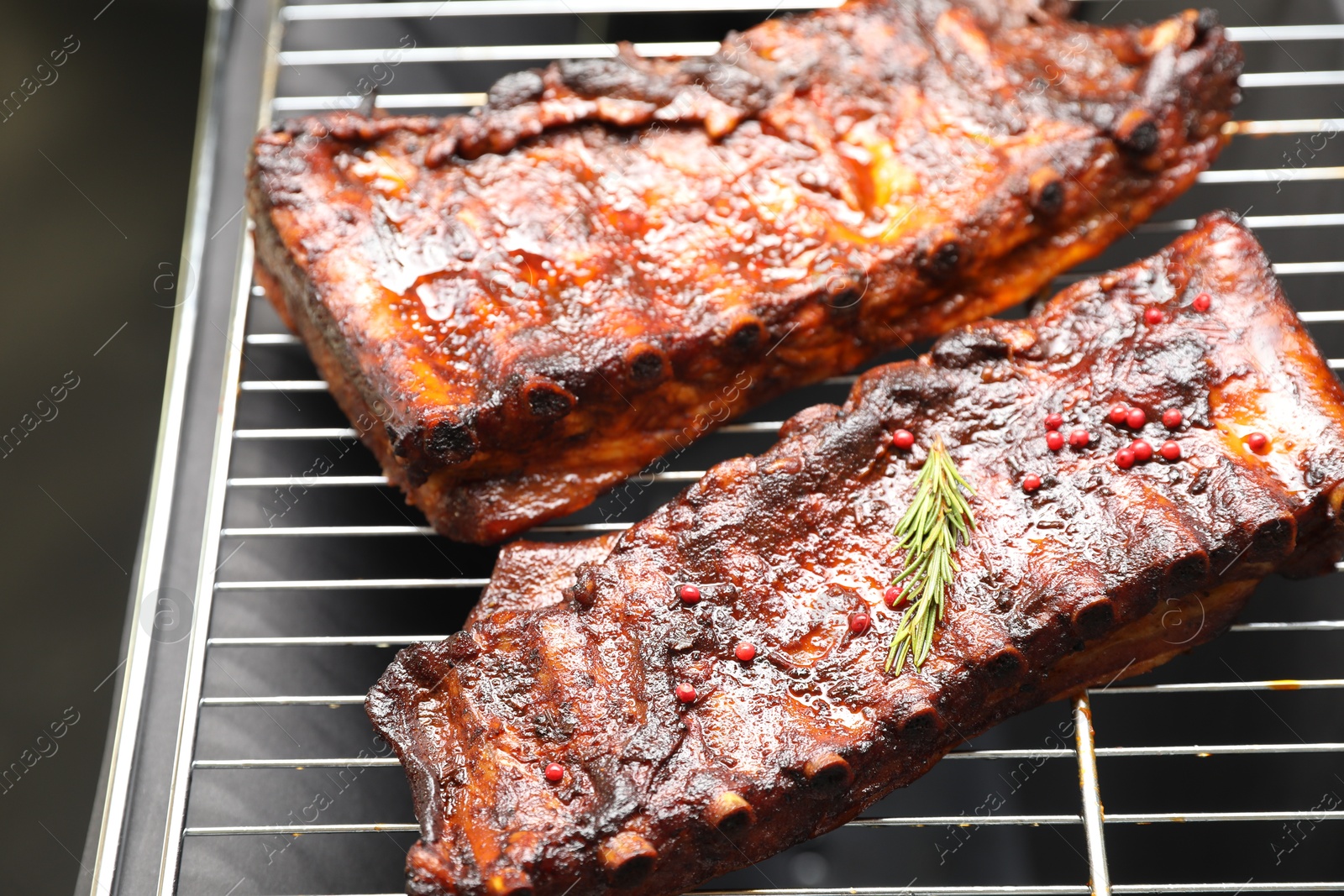 Delicious roasted pork ribs with rosemary on grill, closeup Photo of Delicious roasted pork ribs with rosemary on grill, closeup