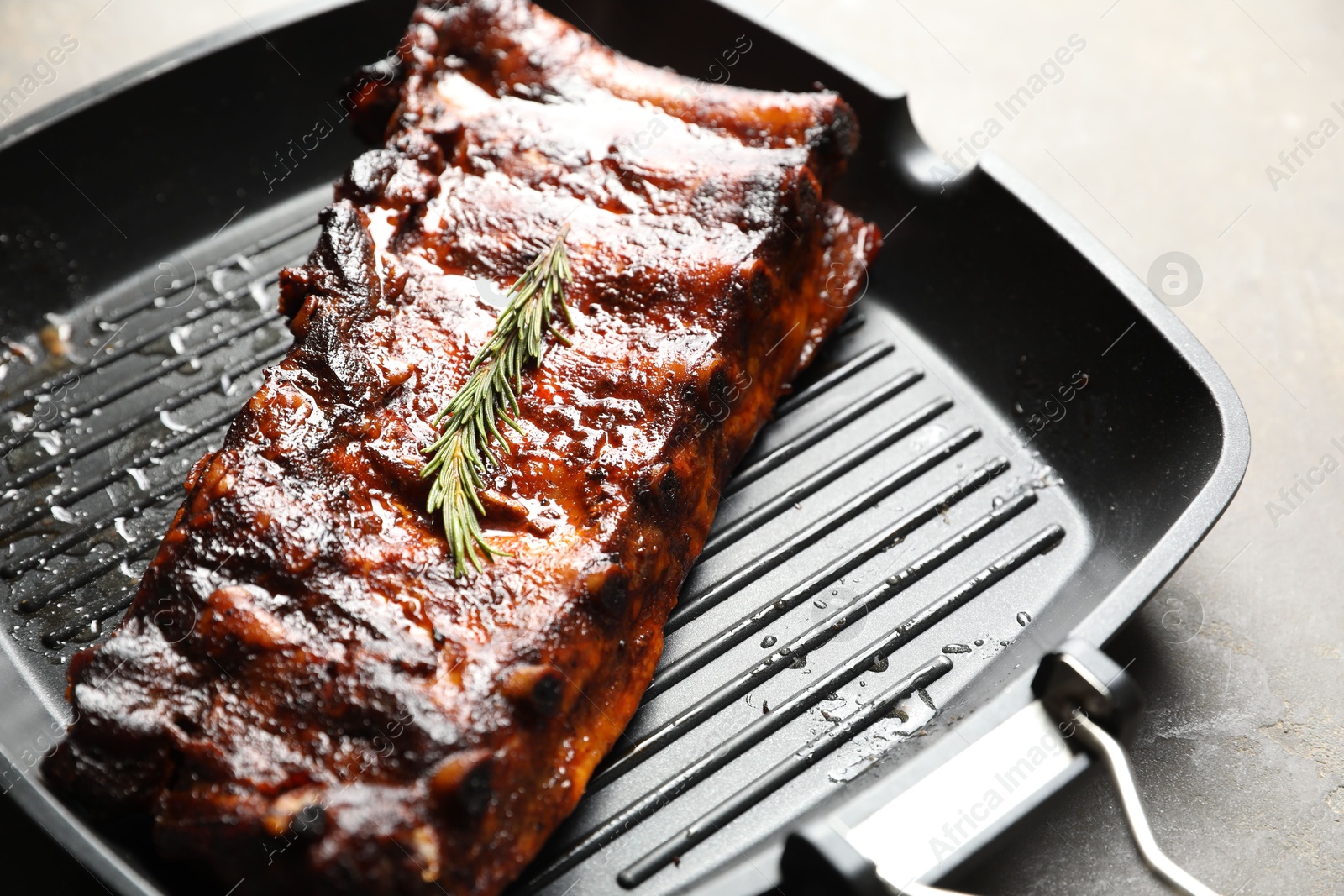 Delicious roasted pork ribs with rosemary on grey table, closeup Photo of Delicious roasted pork ribs with rosemary on grey table, closeup