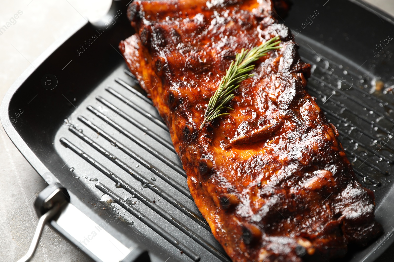 Delicious roasted pork ribs with rosemary on grey table, closeup Photo of Delicious roasted pork ribs with rosemary on grey table, closeup