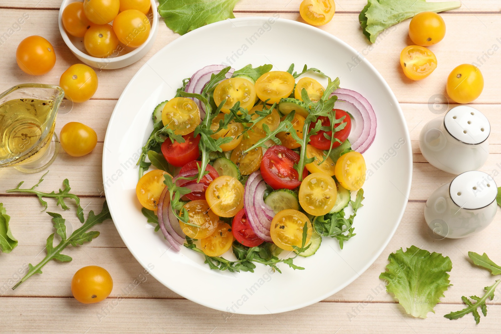 Fresh salad with yellow tomatoes on white wooden table, flat lay Photo of Fresh salad with yellow tomatoes on white wooden table, flat lay