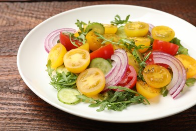 Photo of Fresh salad with yellow tomatoes on wooden table, closeup