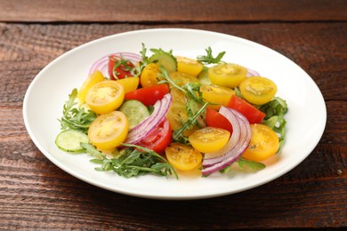 Photo of Fresh salad with yellow tomatoes on wooden table, closeup