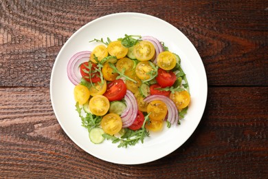 Photo of Fresh salad with yellow tomatoes on wooden table, top view
