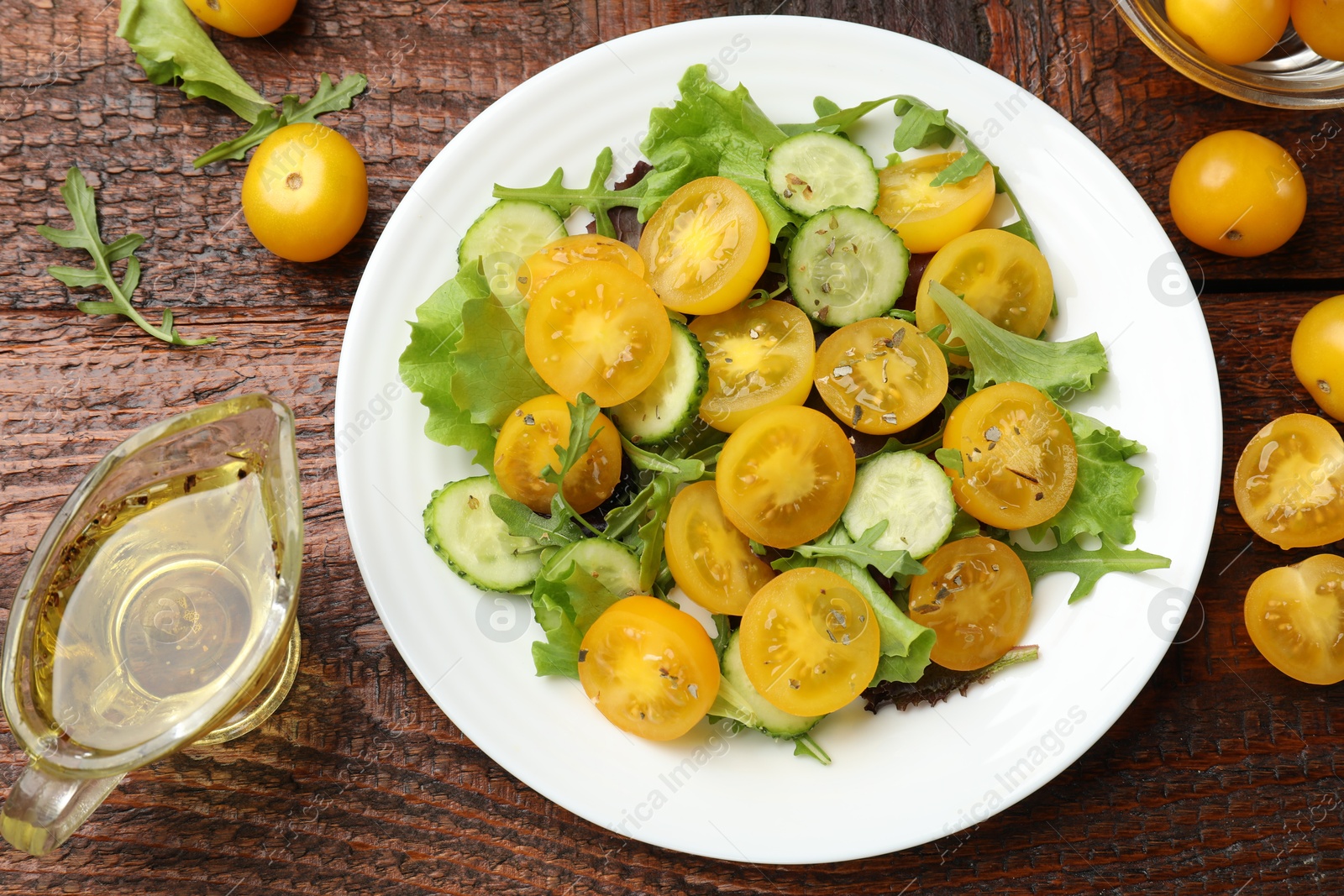 Fresh salad with yellow tomatoes on wooden table, flat lay Photo of Fresh salad with yellow tomatoes on wooden table, flat lay