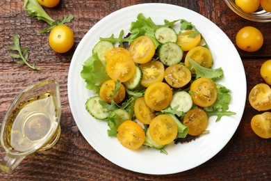 Photo of Fresh salad with yellow tomatoes on wooden table, flat lay