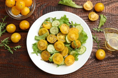 Photo of Fresh salad with yellow tomatoes on wooden table, flat lay