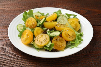 Photo of Fresh salad with yellow tomatoes on wooden table, closeup