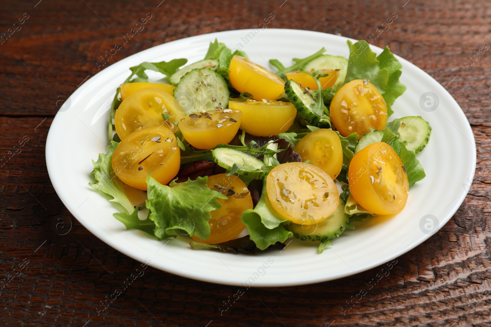 Fresh salad with yellow tomatoes on wooden table, closeup Photo of Fresh salad with yellow tomatoes on wooden table, closeup