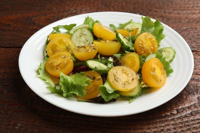 Photo of Fresh salad with yellow tomatoes on wooden table, closeup