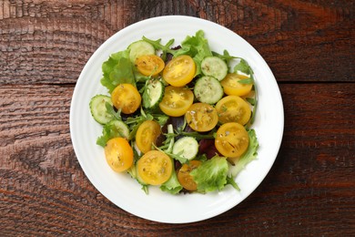 Photo of Fresh salad with yellow tomatoes on wooden table, top view