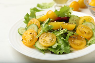 Photo of Fresh salad with yellow tomatoes on white table, closeup