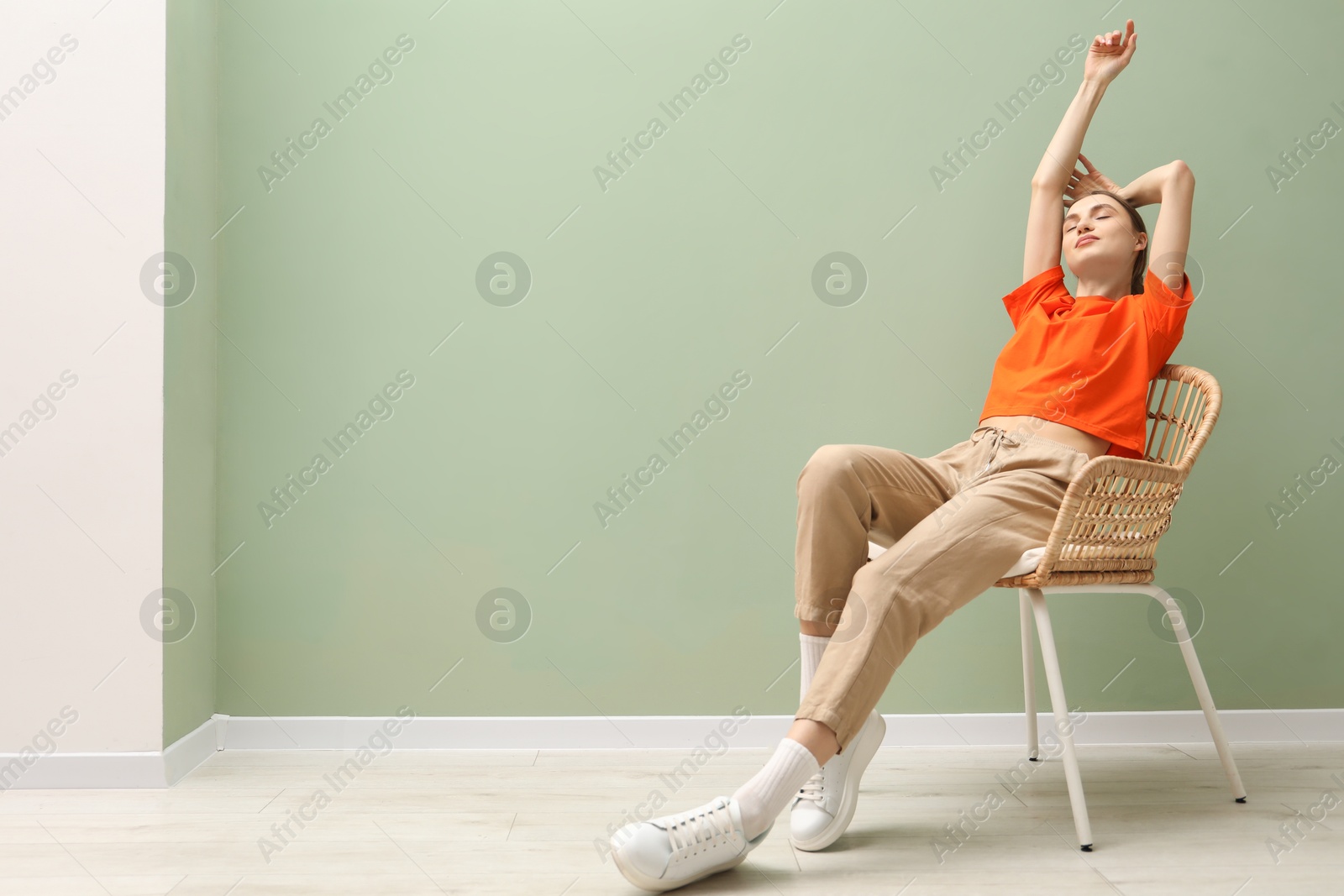 Beautiful woman relaxing in comfortable wicker armchair near pale green wall indoors, space for text Photo of Beautiful woman relaxing in comfortable wicker armchair near pale green wall indoors, space for text