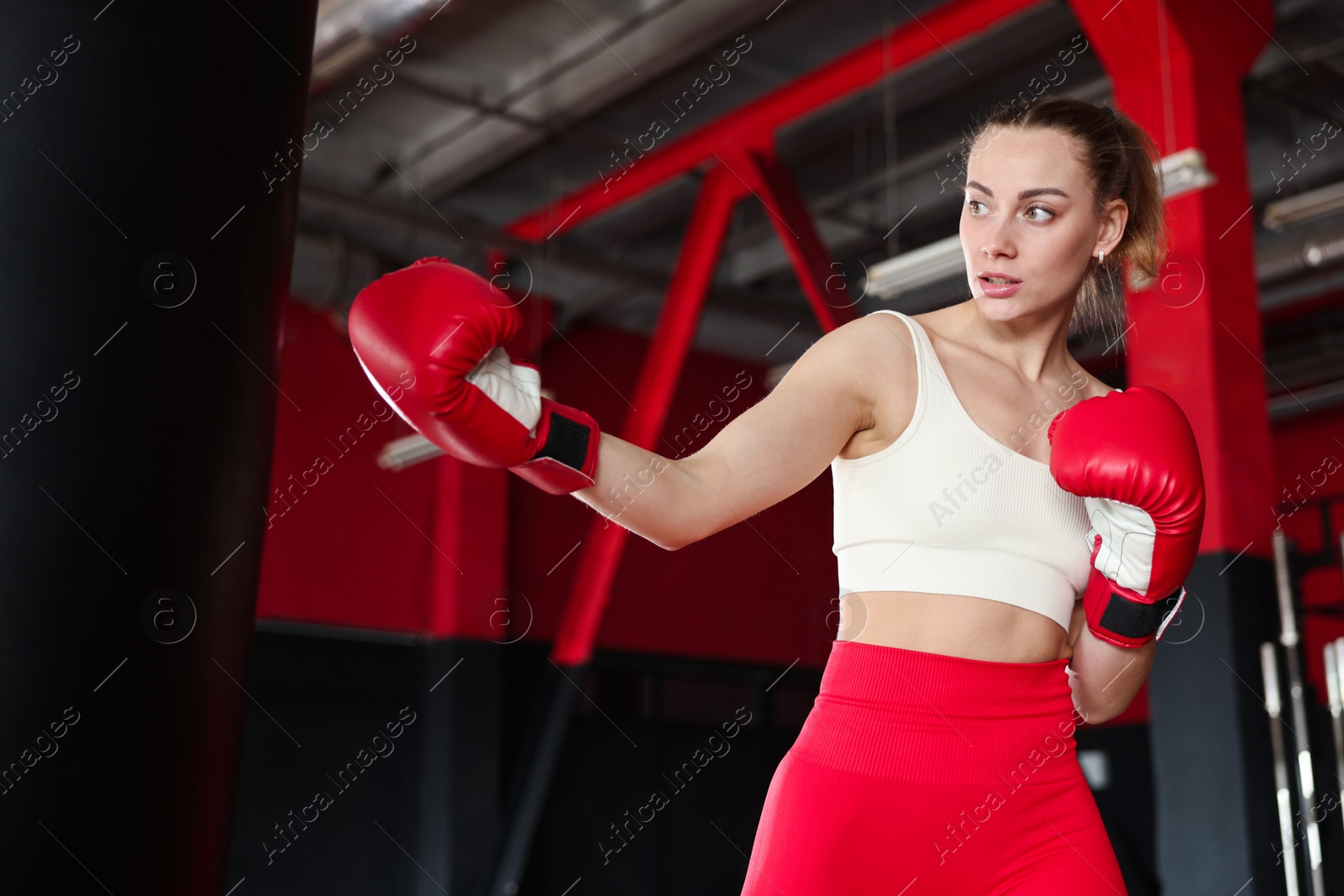 Boxing. Woman practicing with punching bag in training center Photo of Boxing. Woman practicing with punching bag in training center