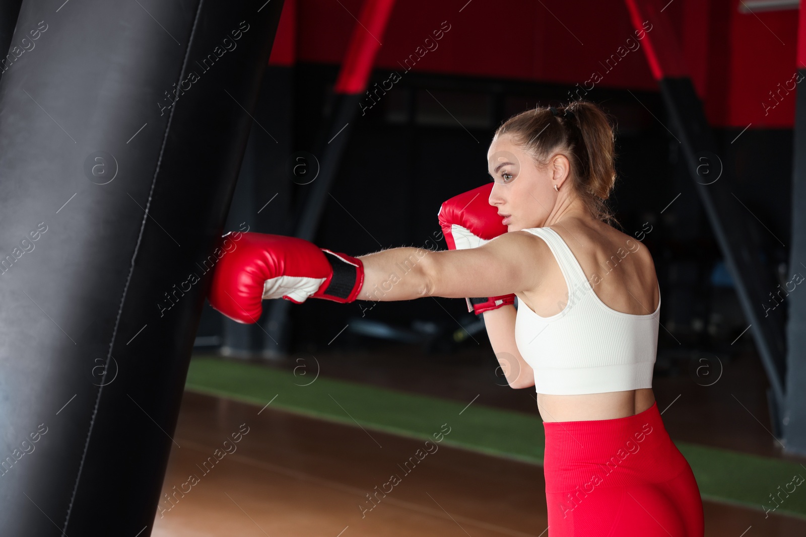 Boxing. Woman practicing with punching bag in training center Photo of Boxing. Woman practicing with punching bag in training center