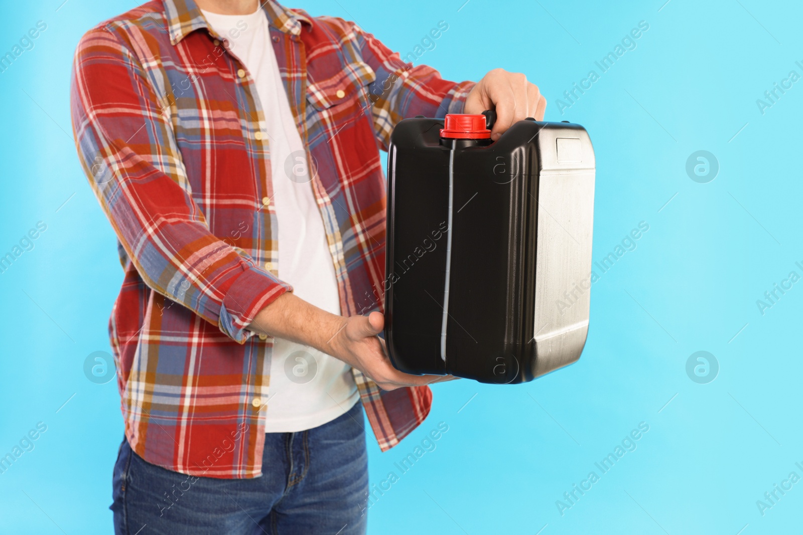 Photo of Man holding plastic canister on light blue background, closeup. Space for text