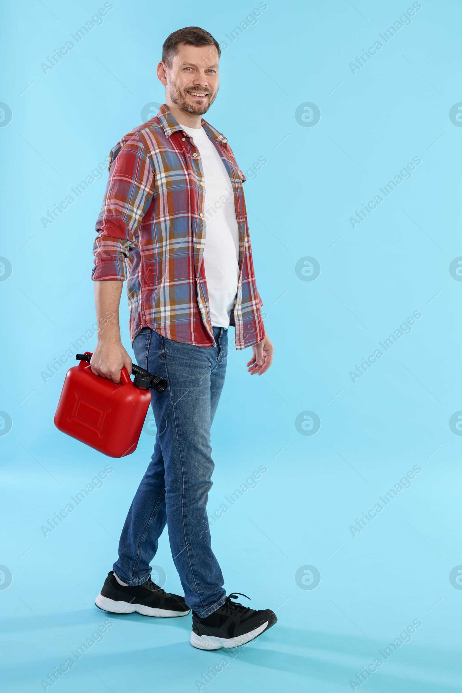 Man holding plastic canister on light blue background, space for text Photo of Man holding plastic canister on light blue background, space for text