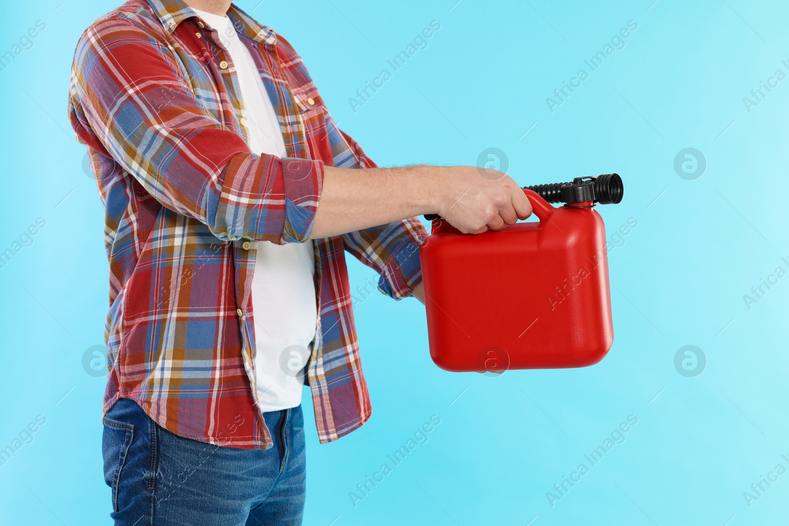 Man holding plastic canister on light blue background, closeup Photo of Man holding plastic canister on light blue background, closeup