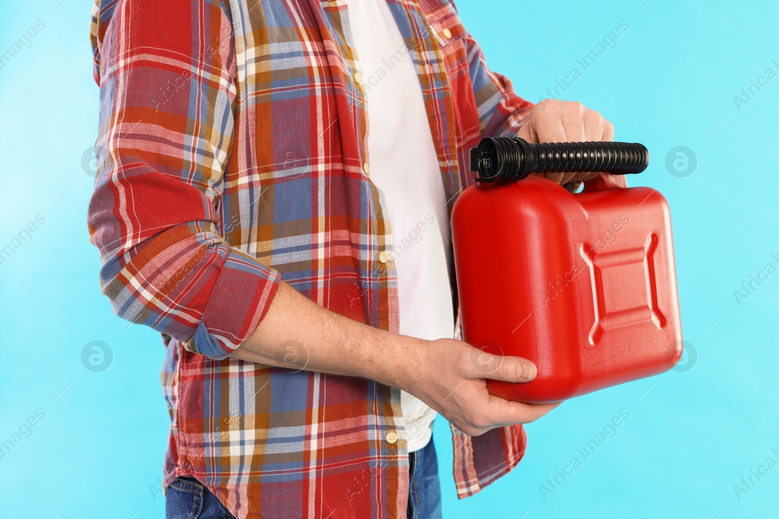 Man holding plastic canister on light blue background, closeup Photo of Man holding plastic canister on light blue background, closeup