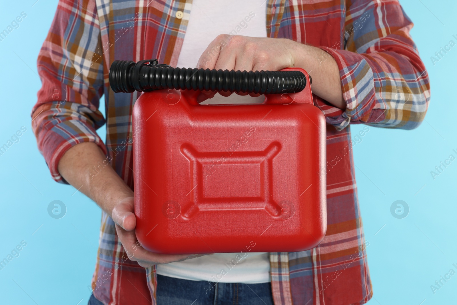 Man holding plastic canister on light blue background, closeup Photo of Man holding plastic canister on light blue background, closeup
