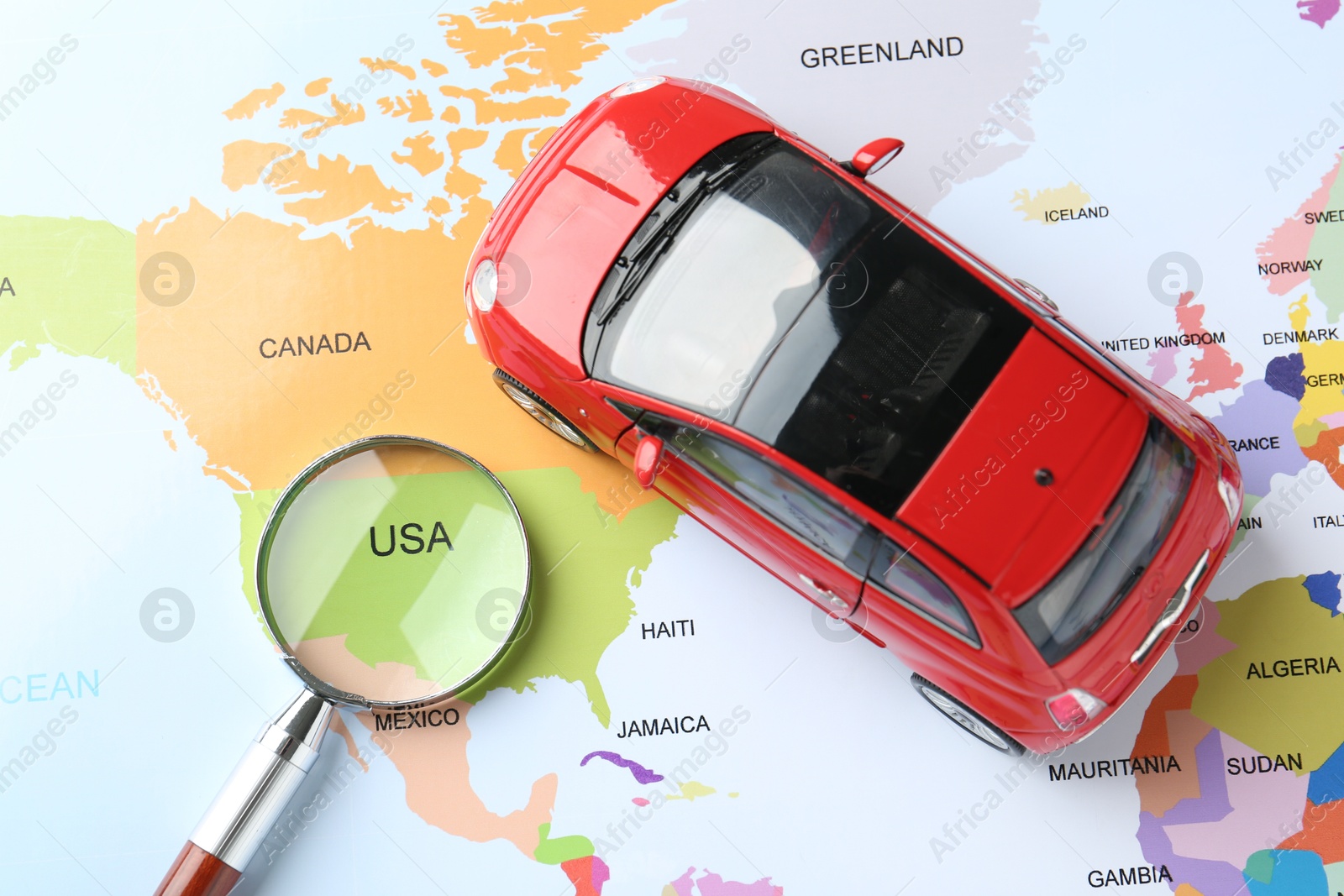 Road trip concept. Car model and magnifying glass on world map, closeup Photo of Road trip concept. Car model and magnifying glass on world map, closeup
