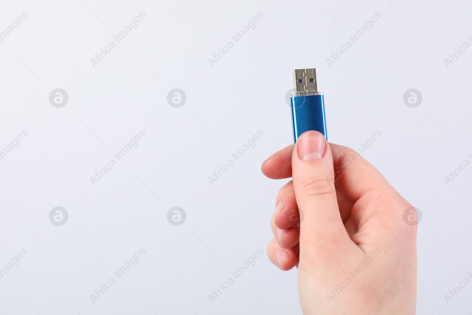 Man with modern flash drive on light grey background, closeup. Space for text Photo of Man with modern flash drive on light grey background, closeup. Space for text