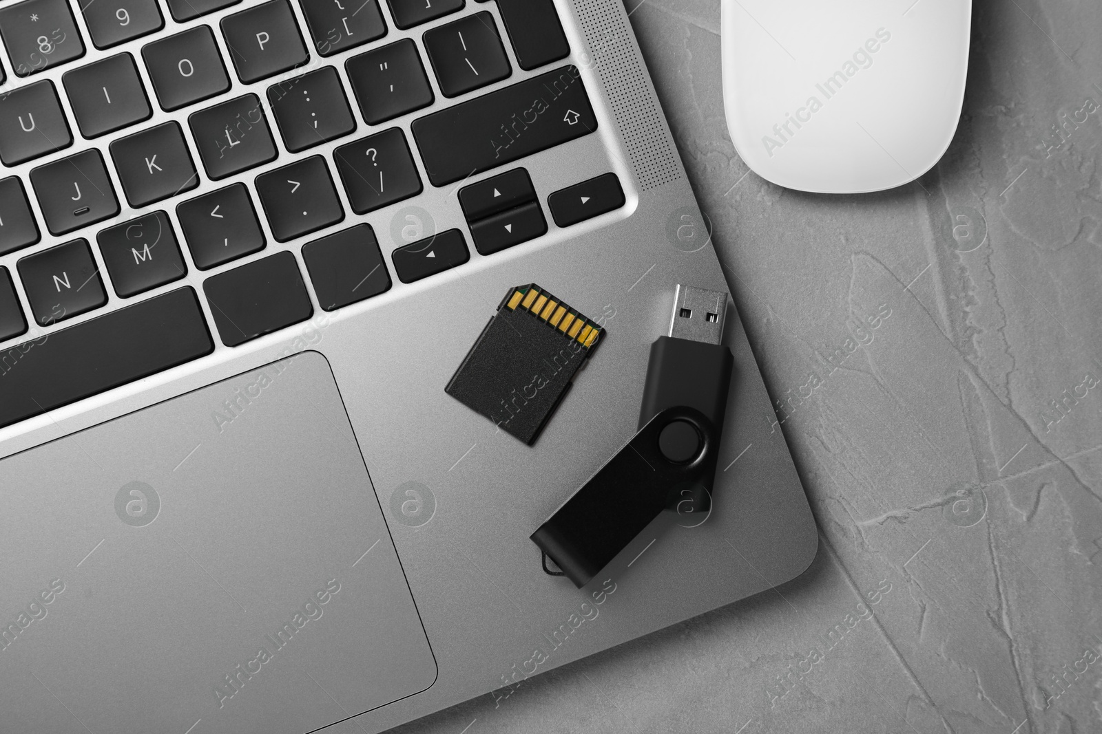 Modern flash drive, SD memory card and laptop on light grey table, flat lay Photo of Modern flash drive, SD memory card and laptop on light grey table, flat lay