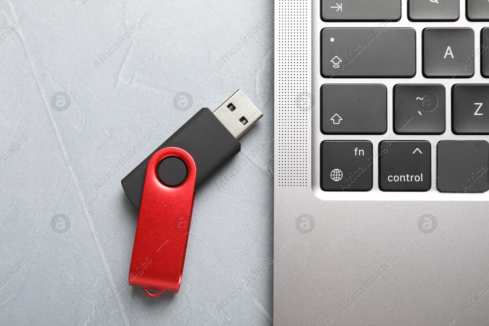 Modern flash drive and laptop on light grey table, flat lay Photo of Modern flash drive and laptop on light grey table, flat lay