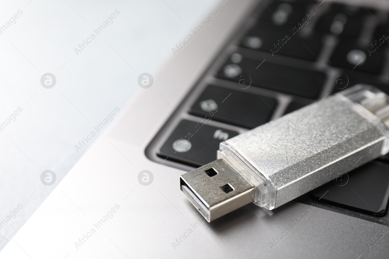 Flash drive and laptop on light grey table, closeup Photo of Flash drive and laptop on light grey table, closeup