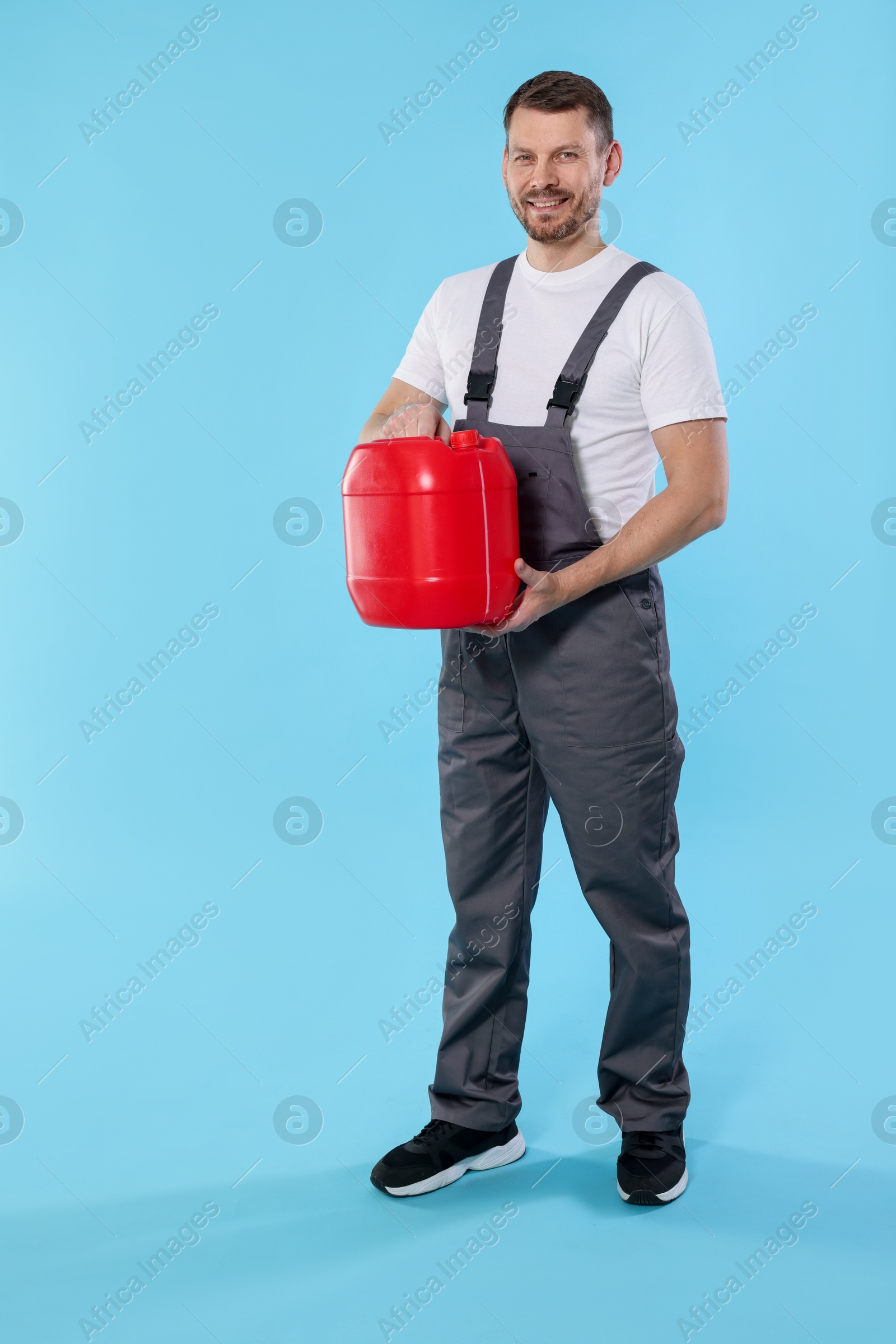 Man holding plastic canister on light blue background Photo of Man holding plastic canister on light blue background