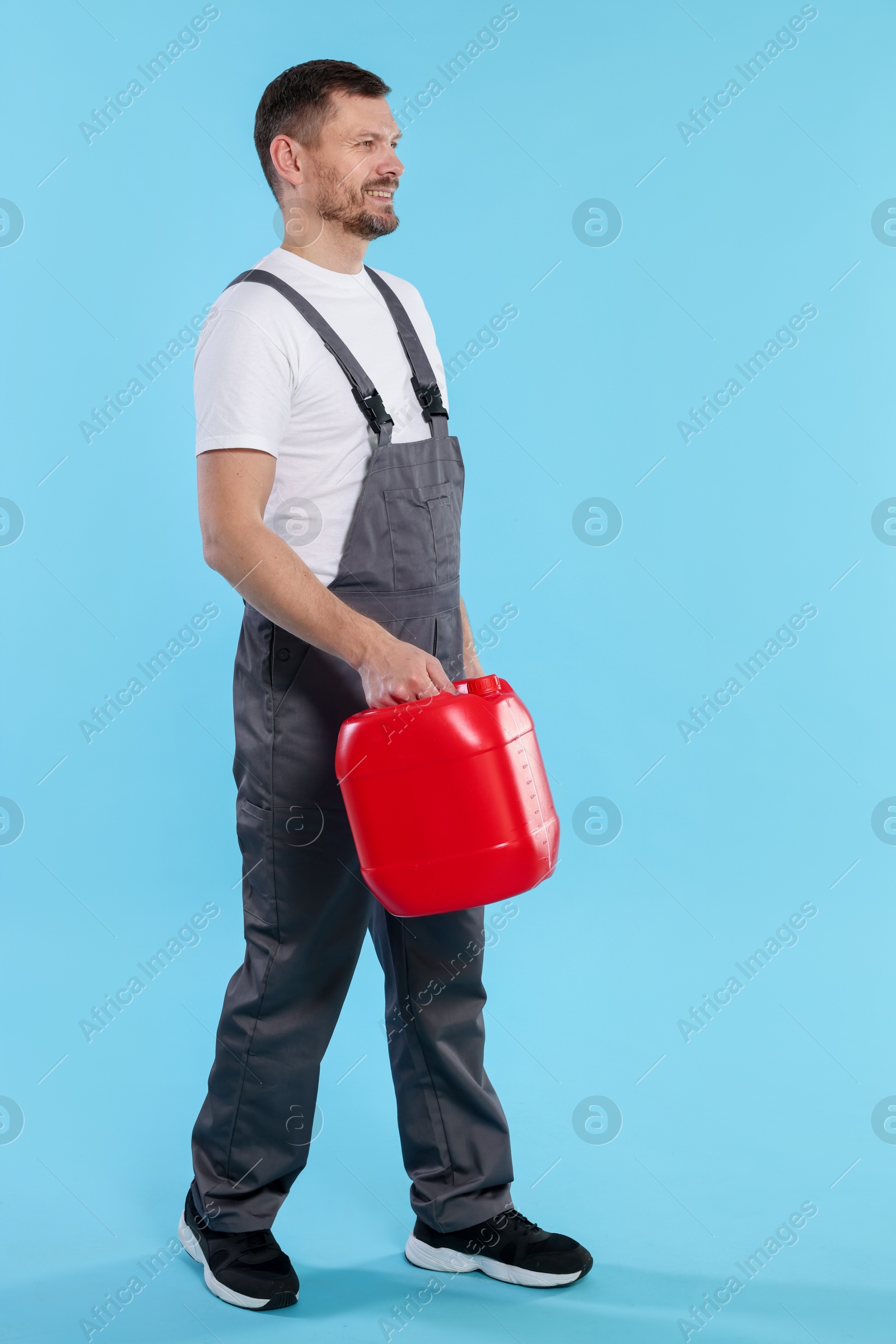 Man holding plastic canister on light blue background Photo of Man holding plastic canister on light blue background