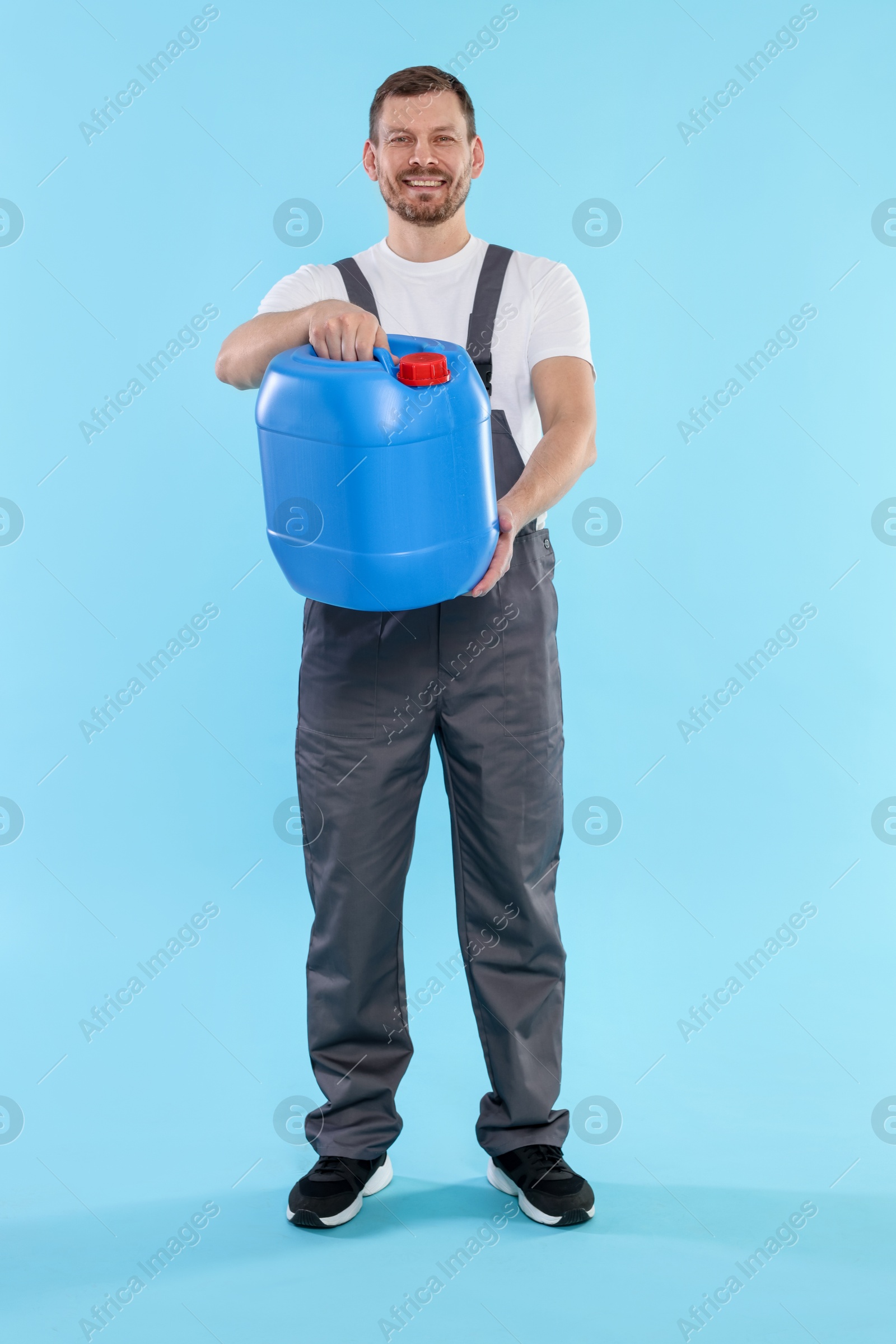 Man holding plastic canister on light blue background Photo of Man holding plastic canister on light blue background