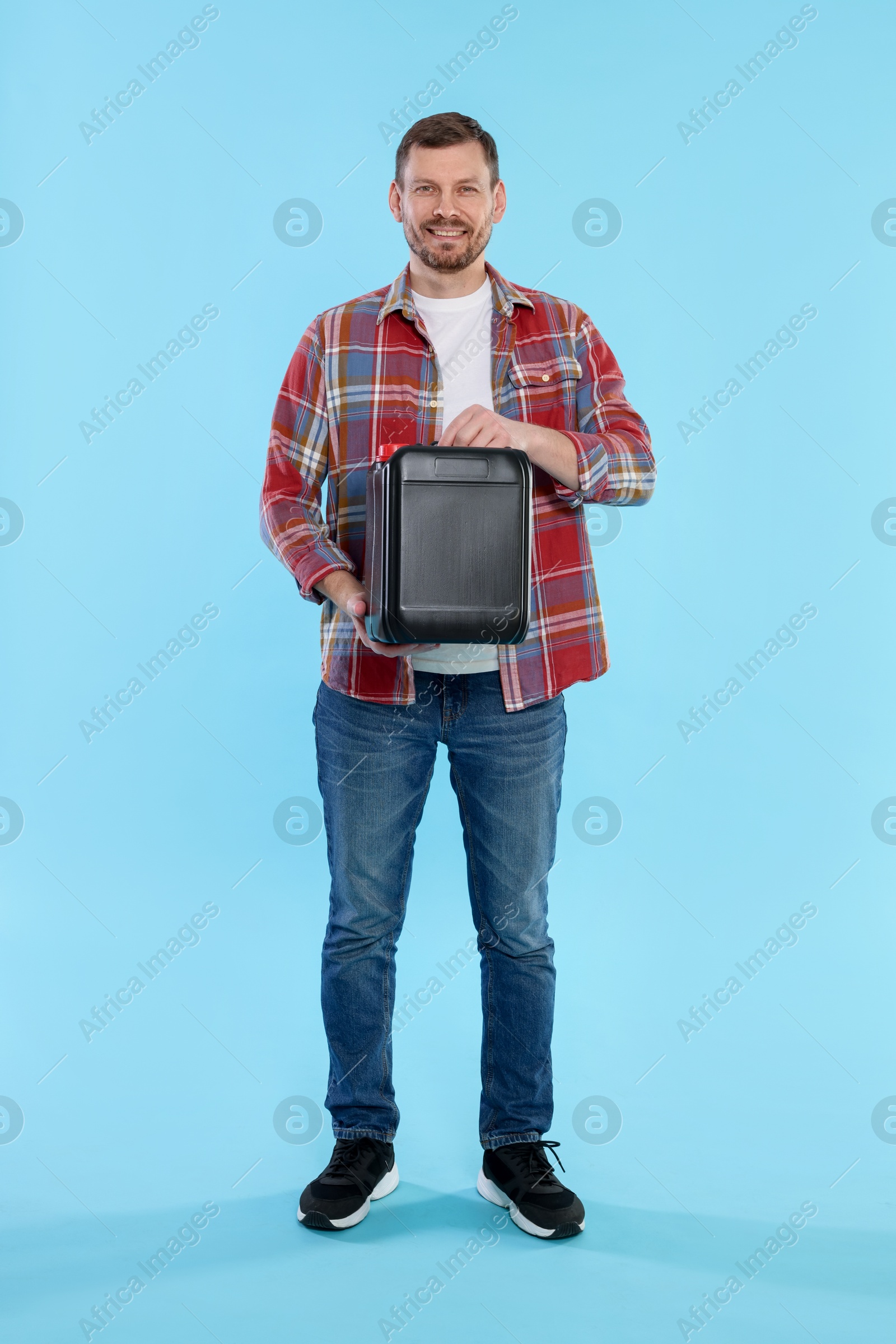 Man holding plastic canister on light blue background Photo of Man holding plastic canister on light blue background