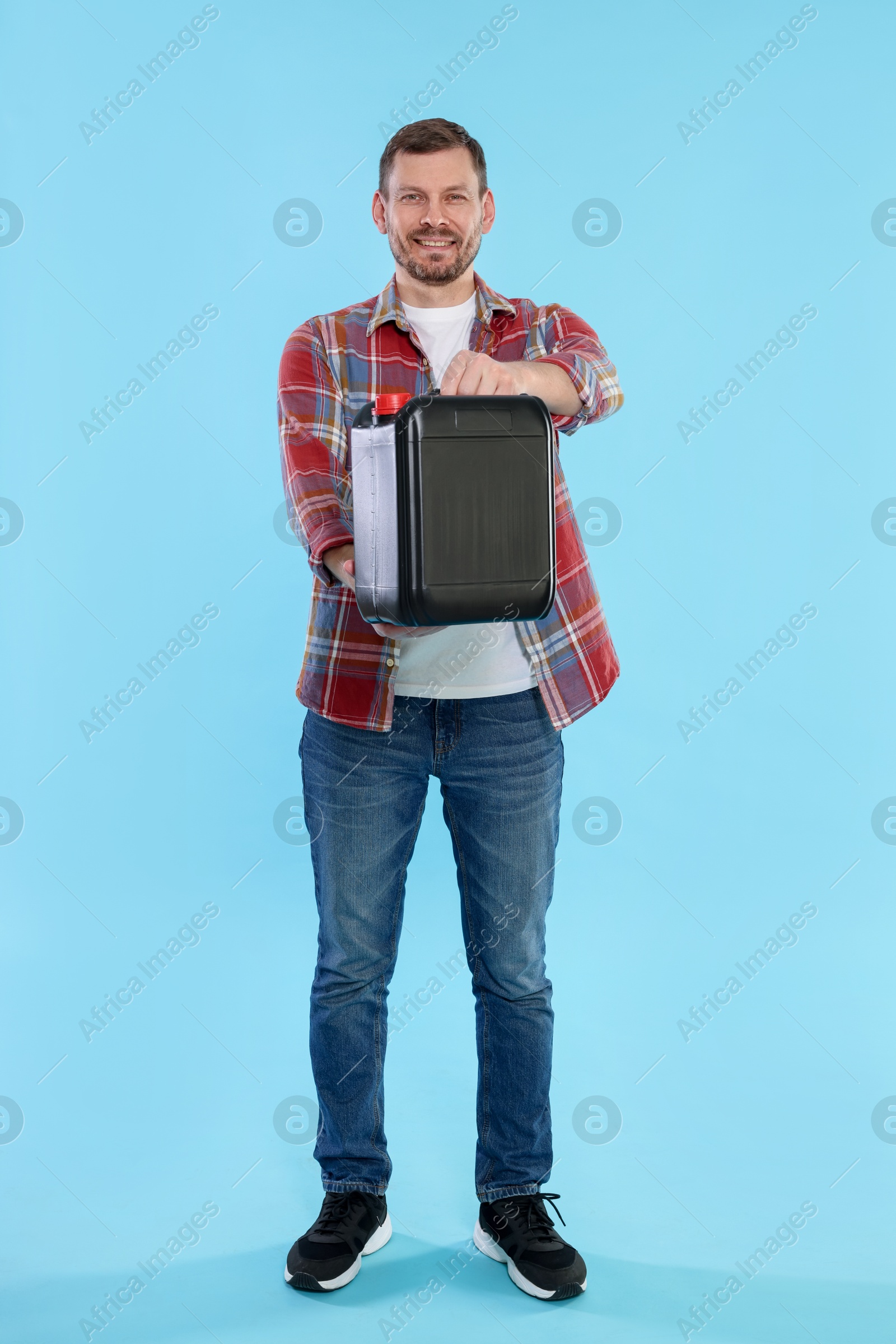 Man holding plastic canister on light blue background Photo of Man holding plastic canister on light blue background