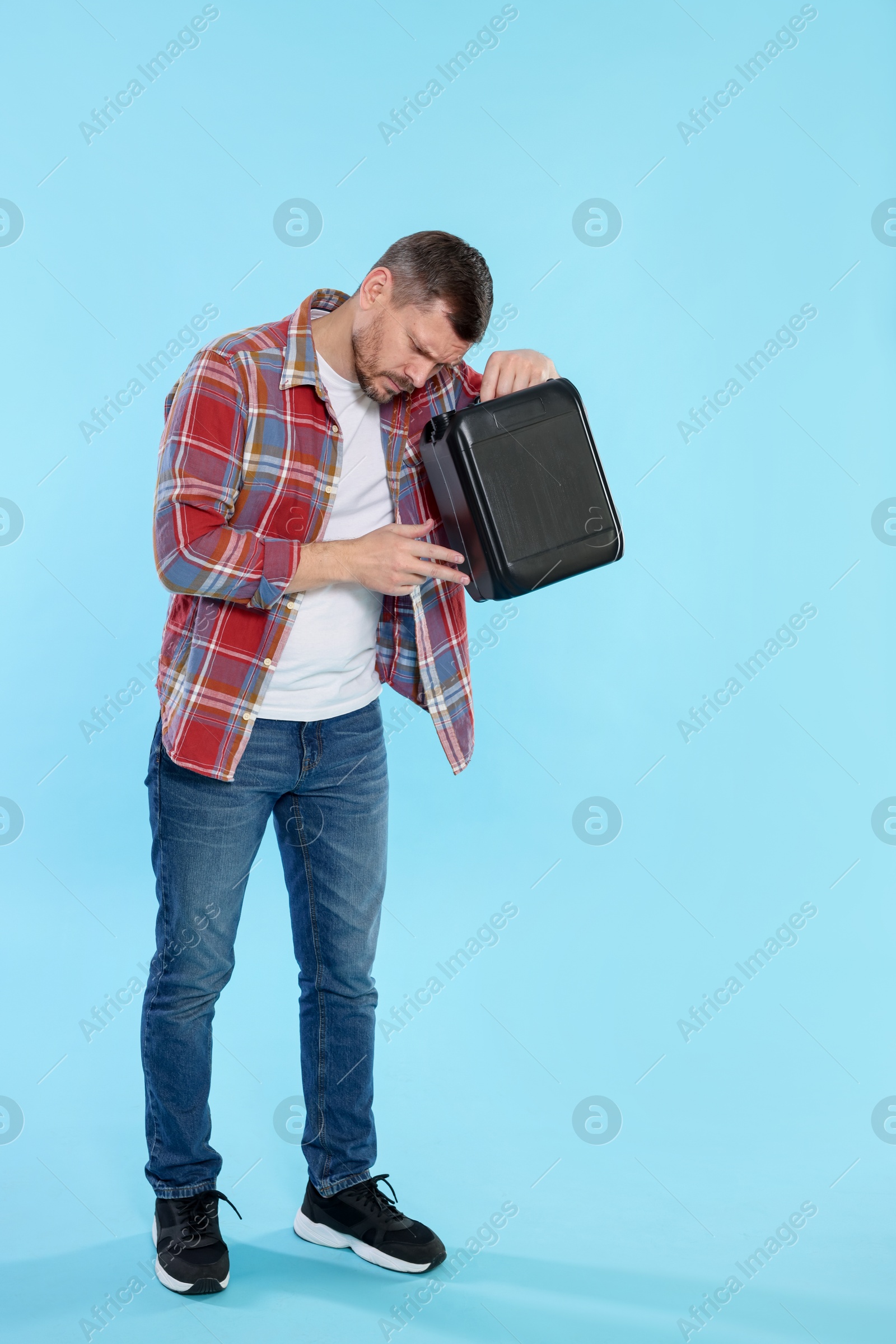 Man holding plastic canister on light blue background, space for text Photo of Man holding plastic canister on light blue background, space for text