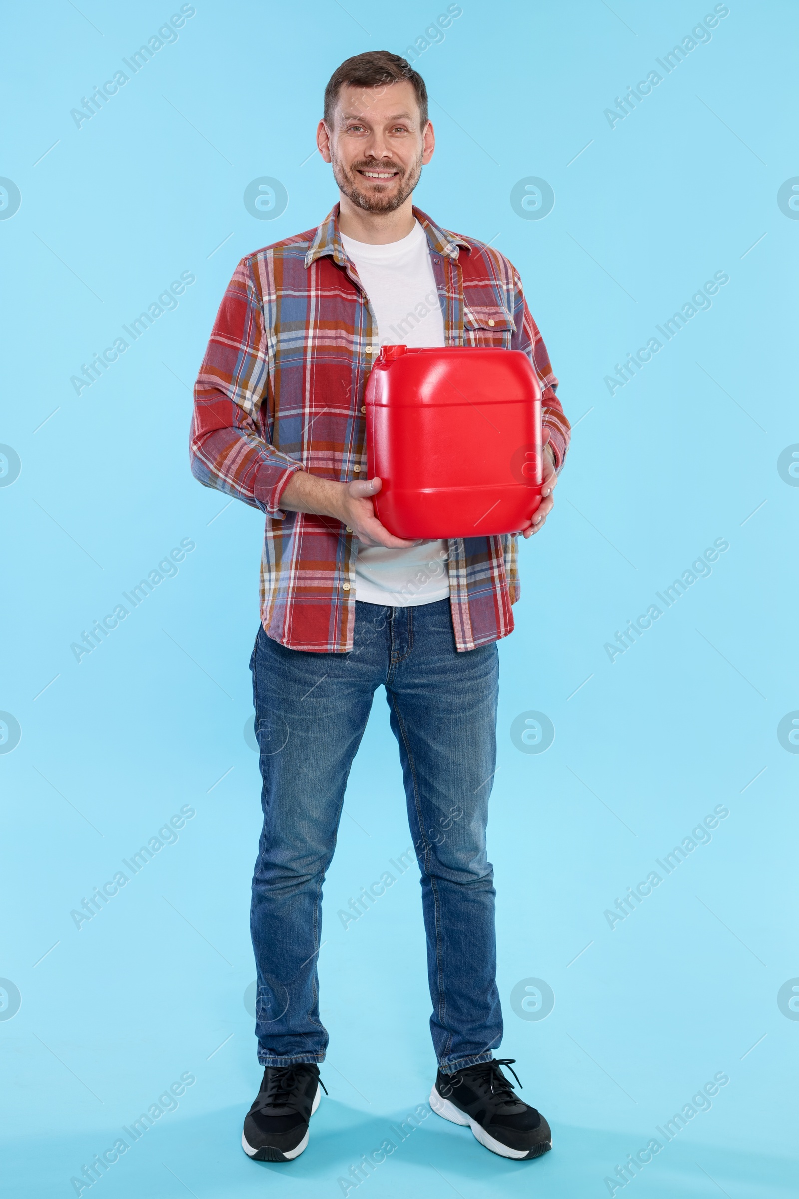Man holding plastic canister on light blue background Photo of Man holding plastic canister on light blue background