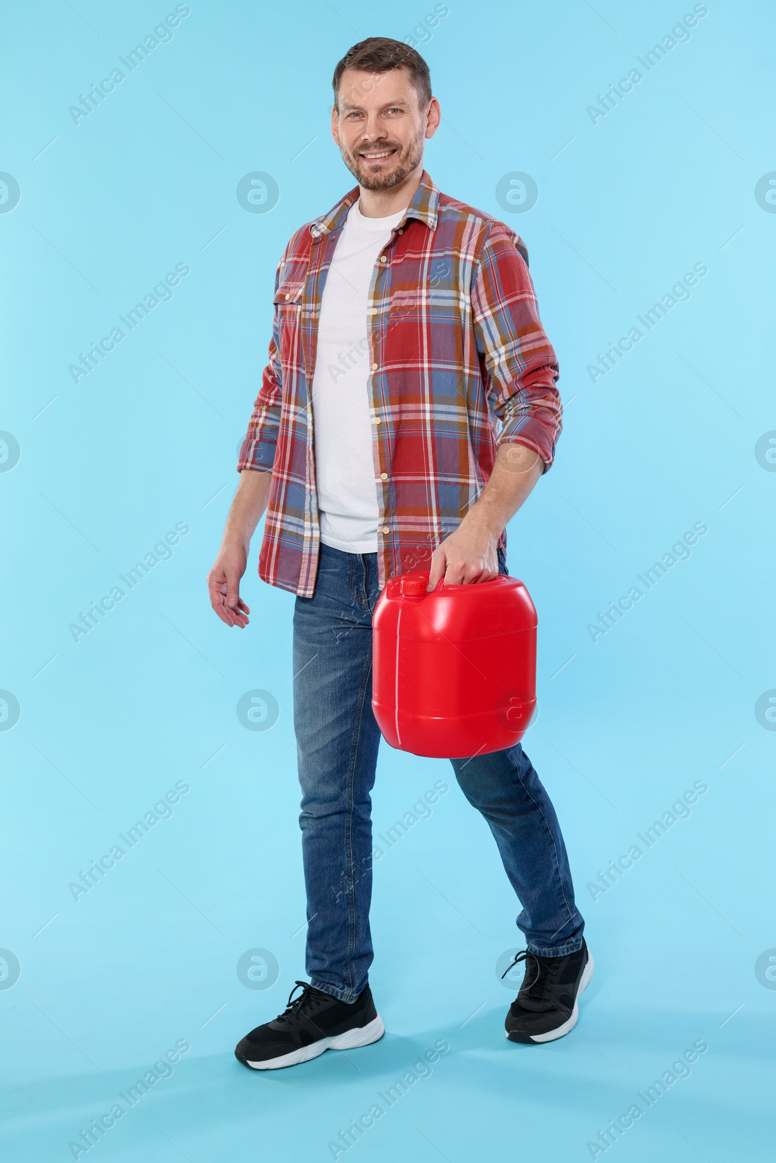Man holding plastic canister on light blue background Photo of Man holding plastic canister on light blue background