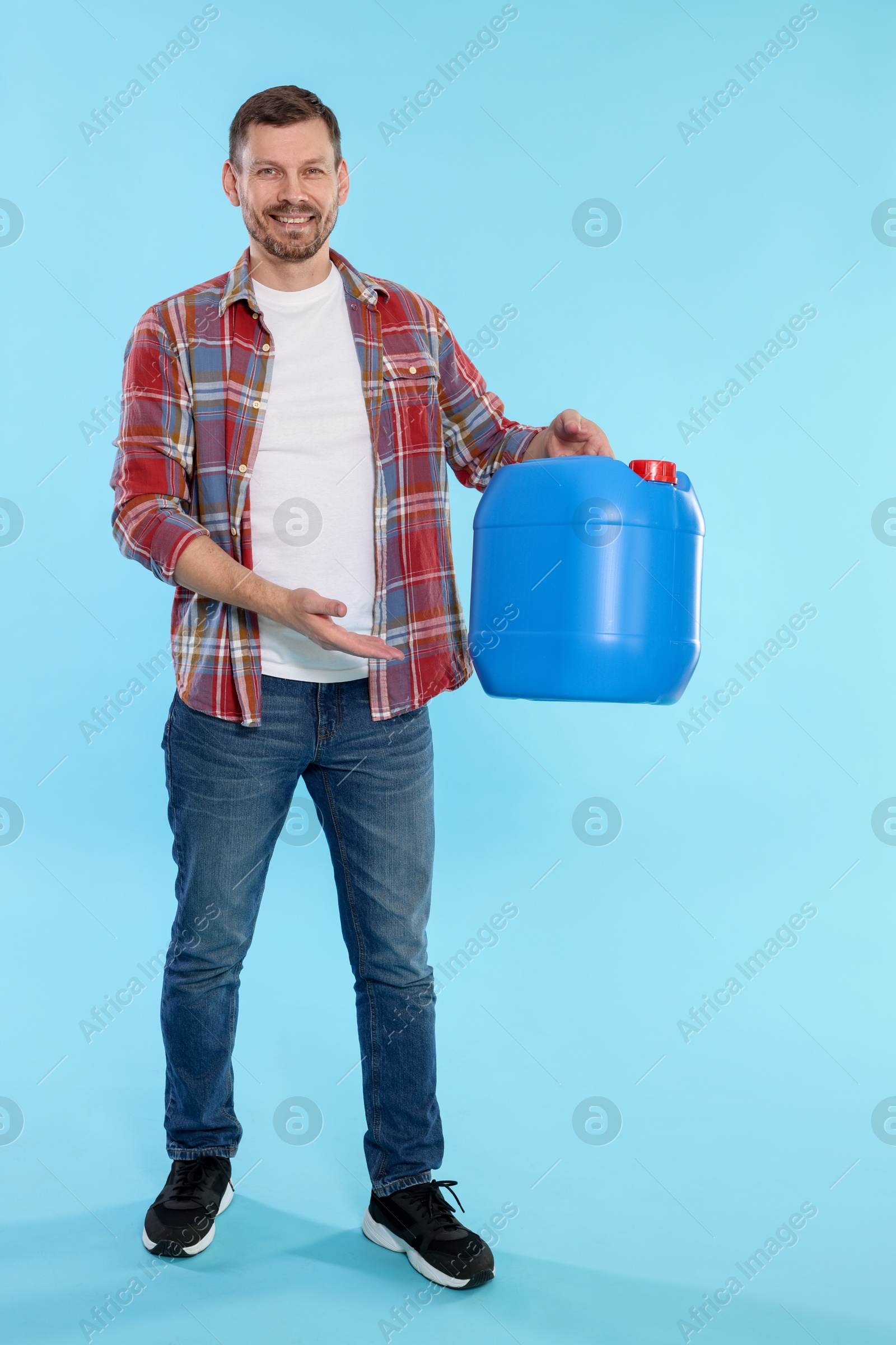 Man holding plastic canister on light blue background Photo of Man holding plastic canister on light blue background