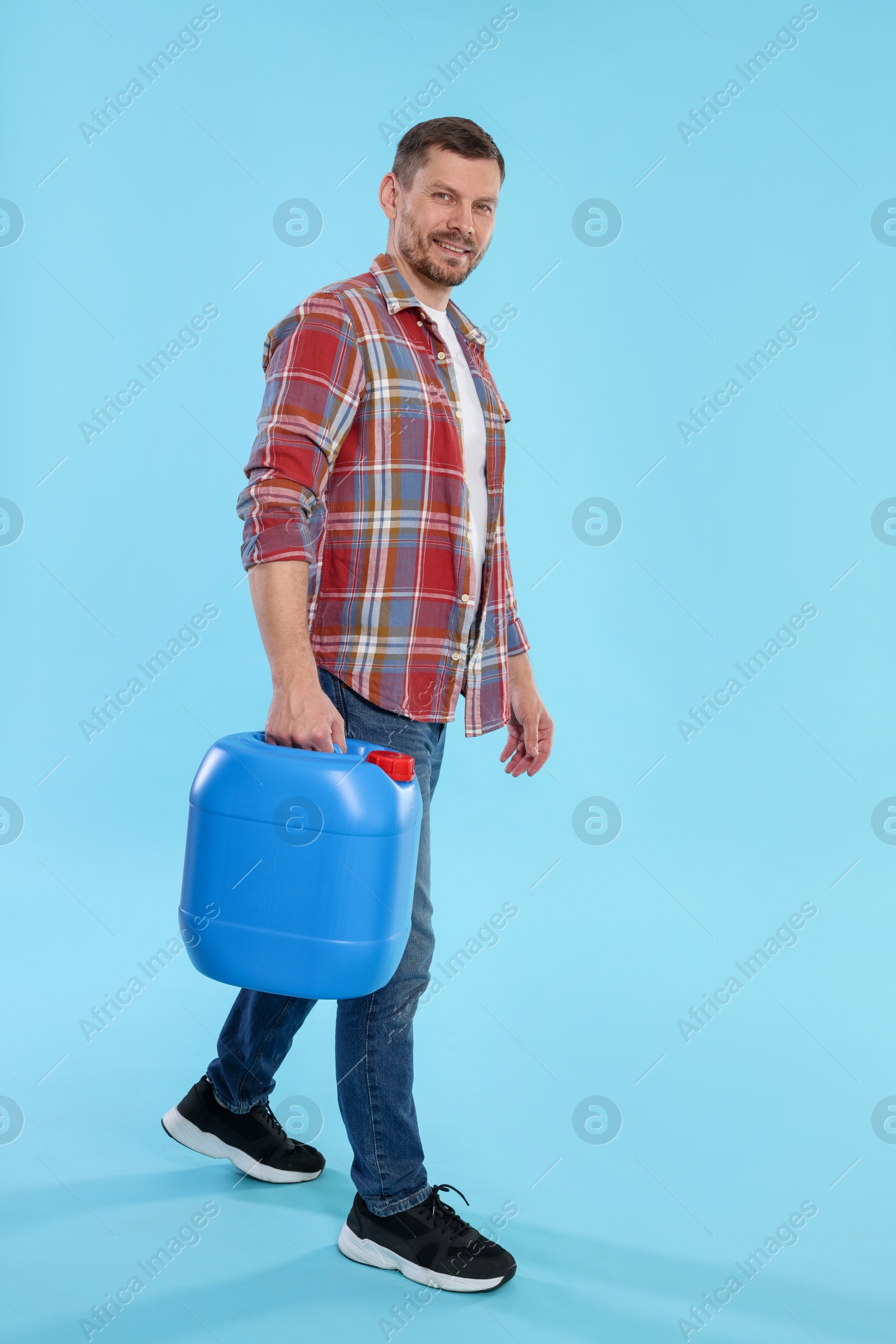 Man holding plastic canister on light blue background, space for text Photo of Man holding plastic canister on light blue background, space for text