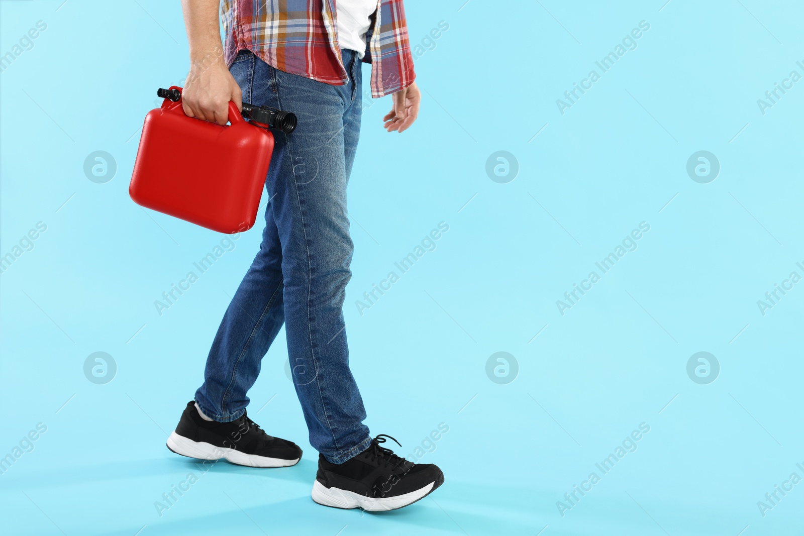Man holding plastic canister on light blue background, closeup. Space for text Photo of Man holding plastic canister on light blue background, closeup. Space for text