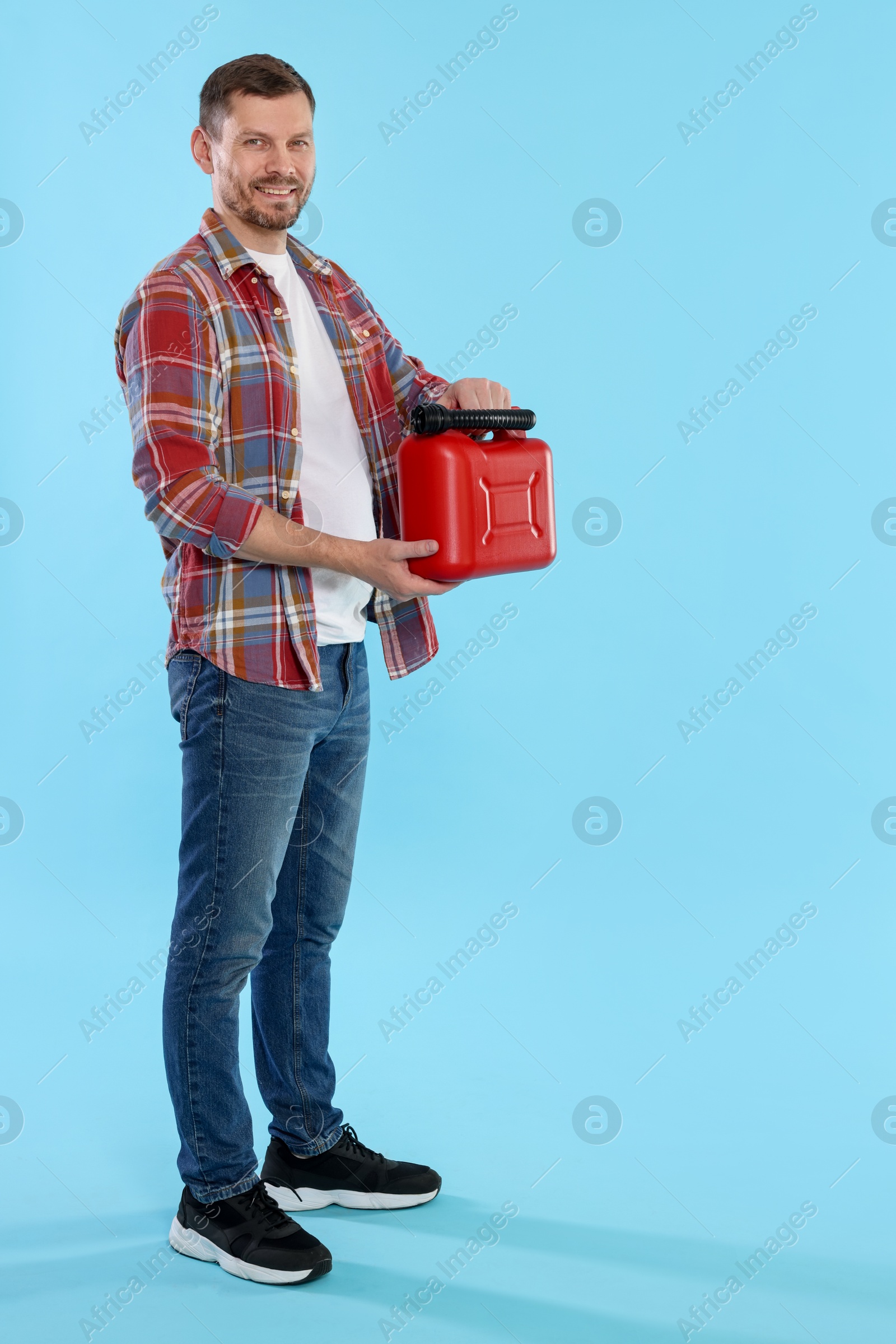 Man holding plastic canister on light blue background, space for text Photo of Man holding plastic canister on light blue background, space for text