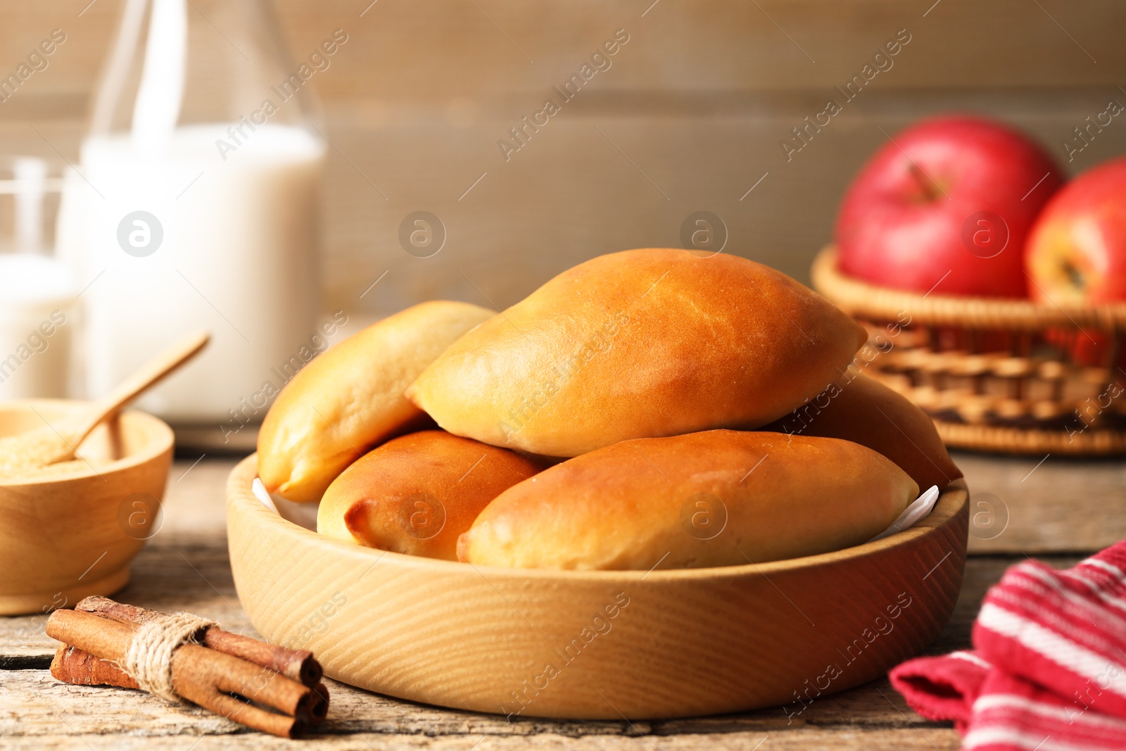 Tasty baked patties and ingredients on wooden table, closeup Photo of Tasty baked patties and ingredients on wooden table, closeup