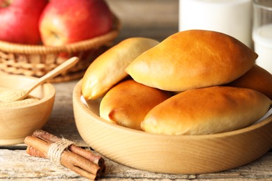 Photo of Tasty baked patties and ingredients on wooden table, closeup
