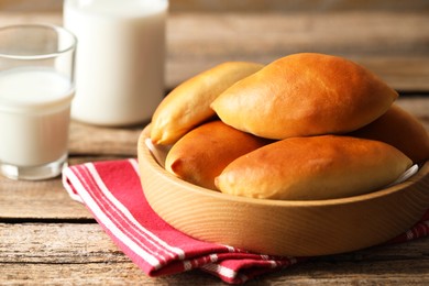 Photo of Tasty baked patties and milk on wooden table, closeup