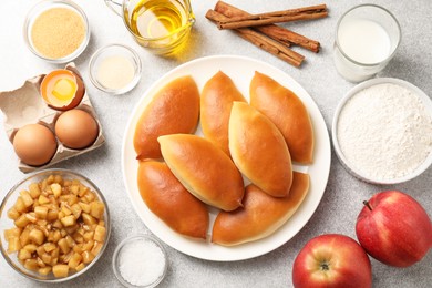 Photo of Tasty baked patties and ingredients on light grey table, flat lay